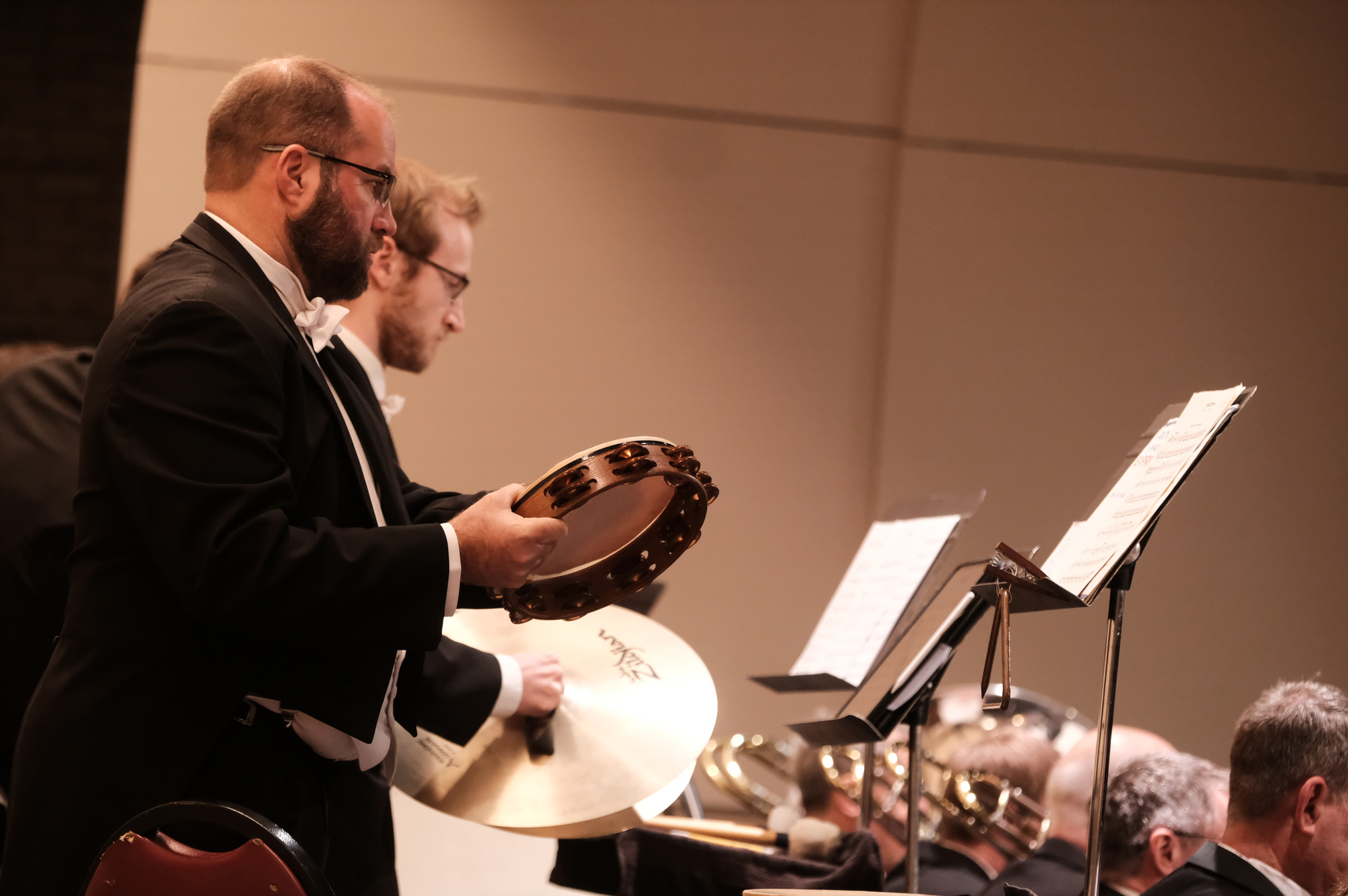 An SBSO percussionist holds a tambourine beside cymbals and music stands.